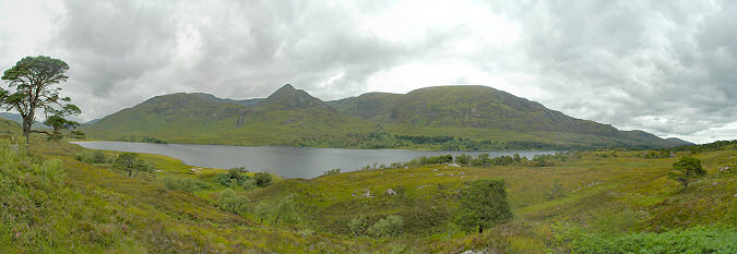 Picture of a view over a glen with a large loch in the centre. Mountains in the background