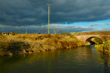 Picture of a bridge over a canal with dramatic clouds overhead
