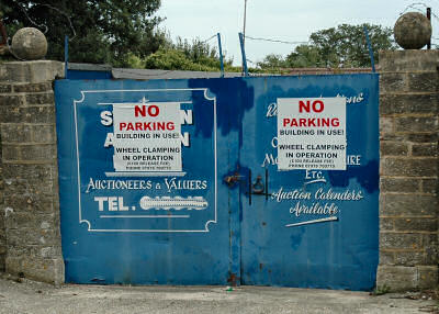 Picture of a gate with signs saying no parking and clamping in operation